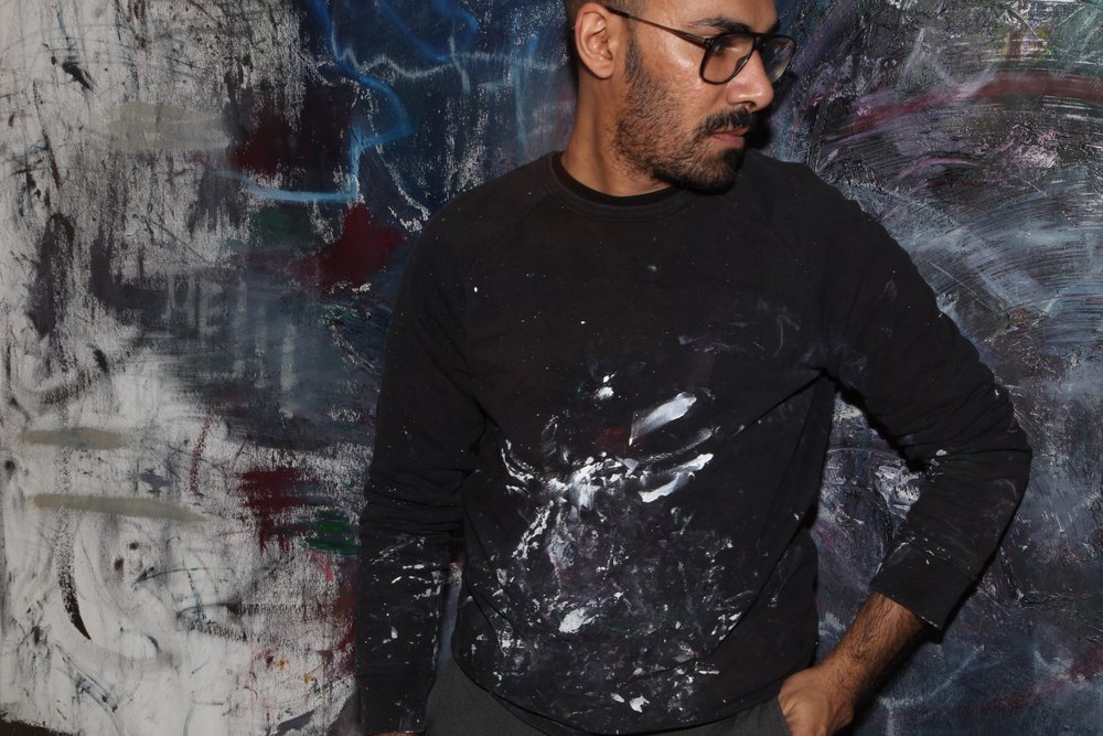 Abdulrahman Hamdi in the studio, in a paint-covered sweater