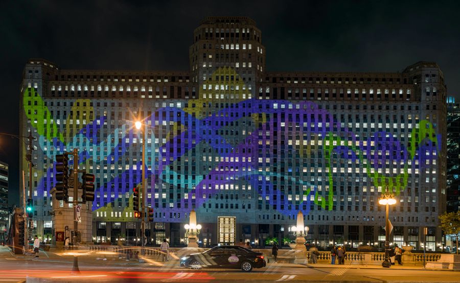 Refusal projected across the facade of THE MART at night, seen from the bridge with passing traffic